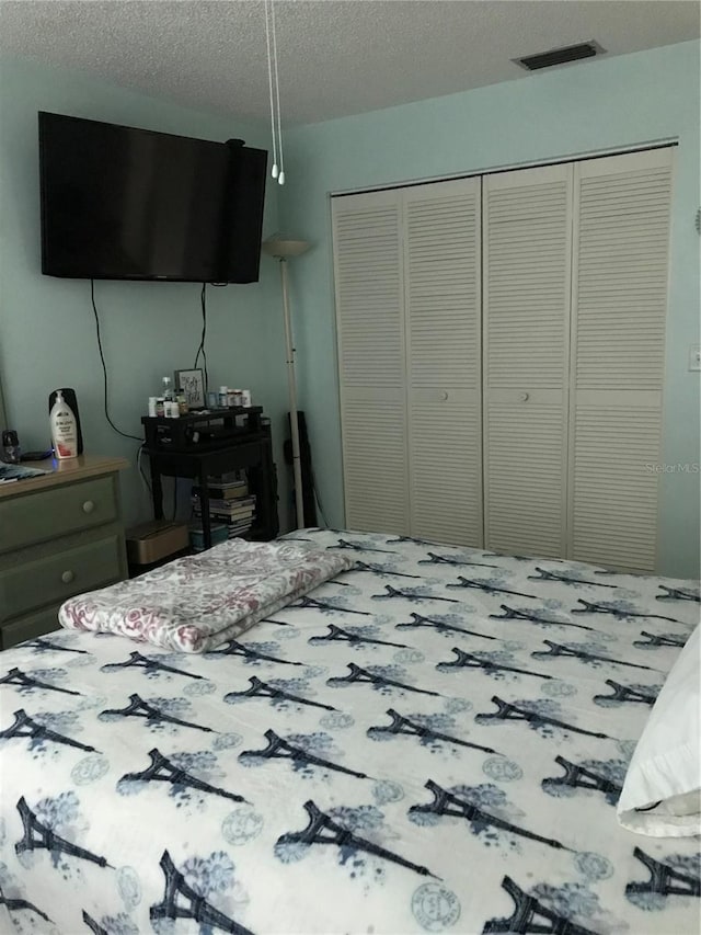 bedroom with a closet, visible vents, and a textured ceiling