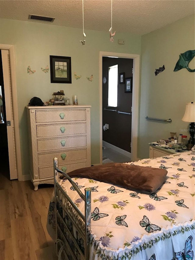 bedroom featuring a textured ceiling, visible vents, and light wood-style floors