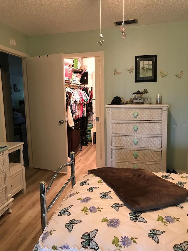 bedroom featuring a closet, a walk in closet, visible vents, and light wood-style floors