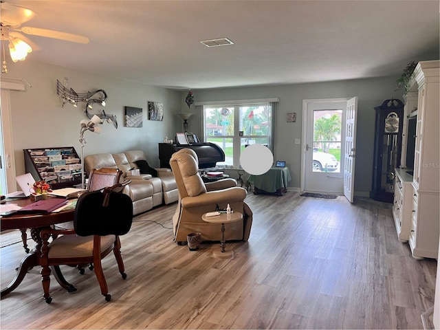 living room with light wood finished floors, visible vents, and baseboards