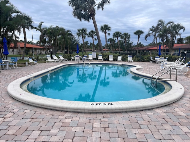 pool with a patio and fence