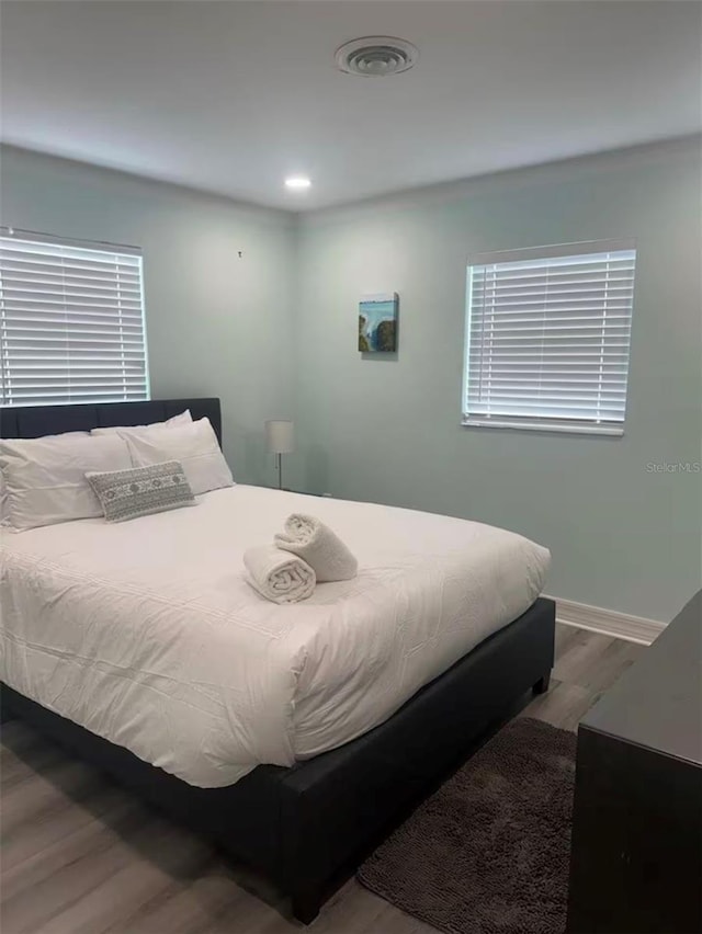 bedroom featuring baseboards, wood finished floors, visible vents, and recessed lighting