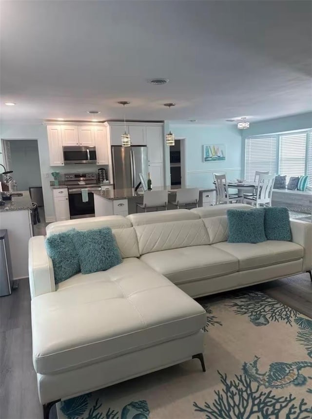 living area with visible vents and wood finished floors