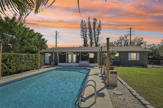 pool at dusk featuring a fenced in pool, a lawn, a sunroom, fence, and a patio area