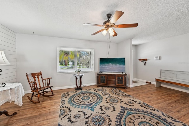 sitting room featuring baseboards, a textured ceiling, a ceiling fan, and wood finished floors