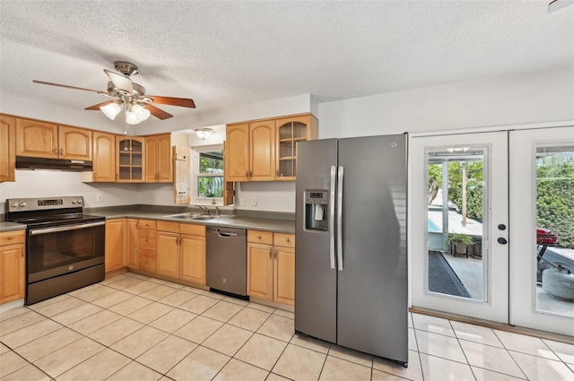 kitchen with stainless steel appliances, a healthy amount of sunlight, glass insert cabinets, and under cabinet range hood