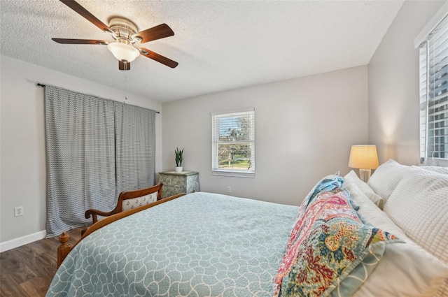 bedroom with a ceiling fan, a textured ceiling, baseboards, and wood finished floors