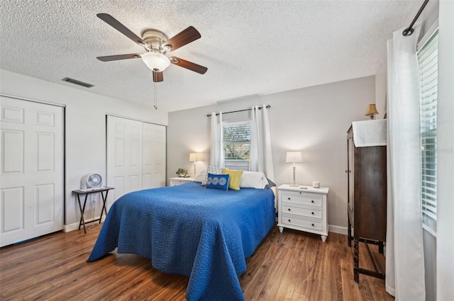 bedroom featuring baseboards, visible vents, a ceiling fan, wood finished floors, and a textured ceiling