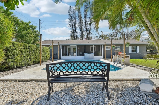 rear view of property featuring a sunroom, a patio area, an outdoor pool, and fence