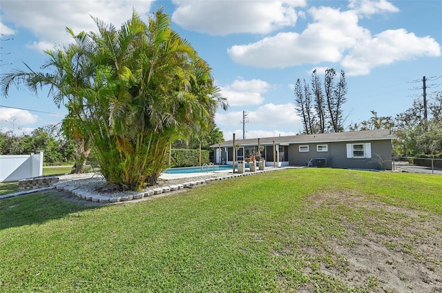 rear view of property featuring a fenced in pool, a sunroom, a lawn, and fence