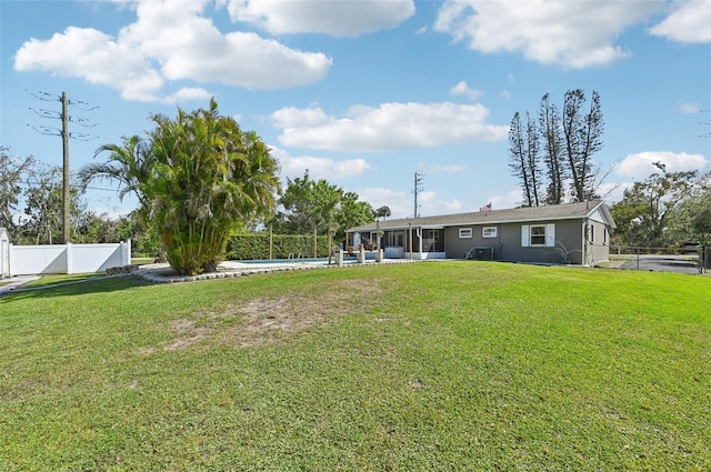 back of house featuring a lawn, a fenced backyard, a sunroom, and a fenced in pool