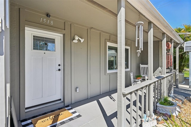 property entrance featuring covered porch and board and batten siding