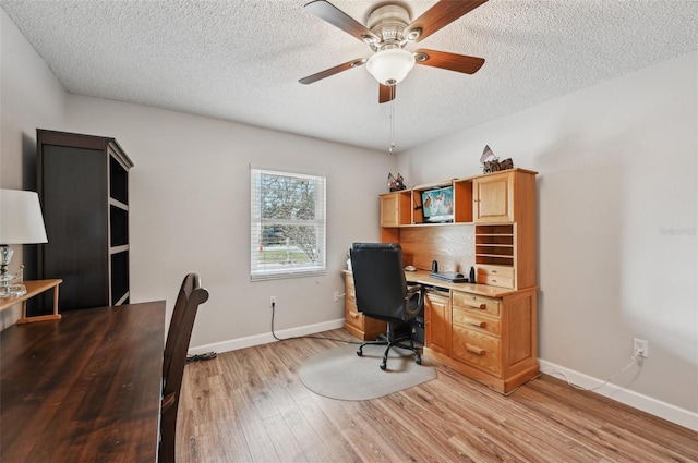 office space with a textured ceiling, ceiling fan, baseboards, and light wood-style floors