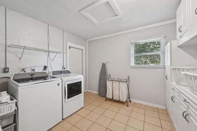 laundry area with cabinet space, attic access, a textured ceiling, separate washer and dryer, and light tile patterned flooring