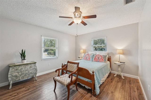 bedroom with a textured ceiling, wood finished floors, a ceiling fan, visible vents, and baseboards