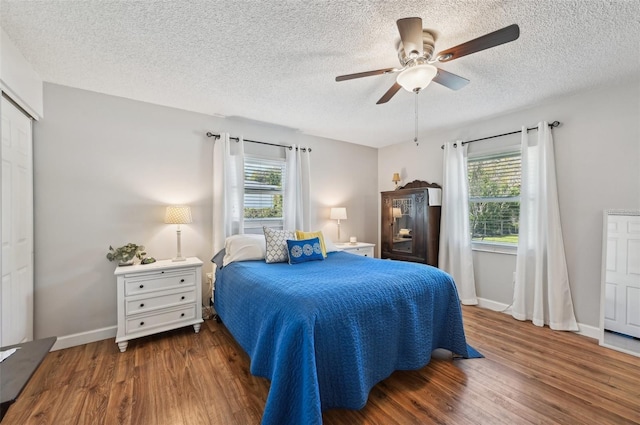 bedroom with multiple windows, wood finished floors, and a ceiling fan