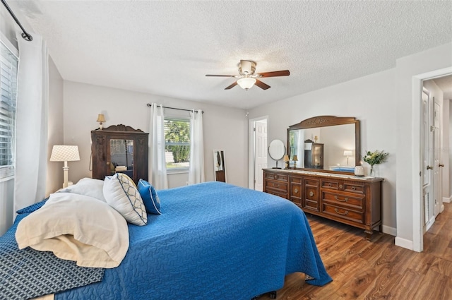 bedroom featuring ceiling fan, a textured ceiling, baseboards, and wood finished floors