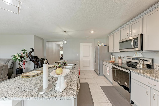 kitchen featuring a kitchen island with sink, appliances with stainless steel finishes, a sink, and light tile patterned flooring