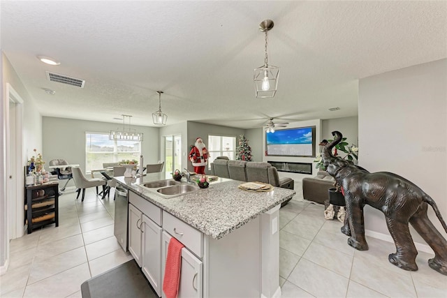 kitchen with a kitchen island with sink, a sink, hanging light fixtures, and stainless steel dishwasher