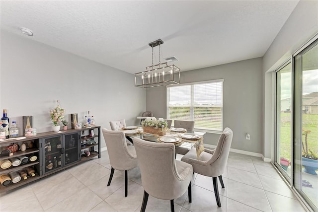 dining area with a textured ceiling, a chandelier, light tile patterned flooring, visible vents, and baseboards