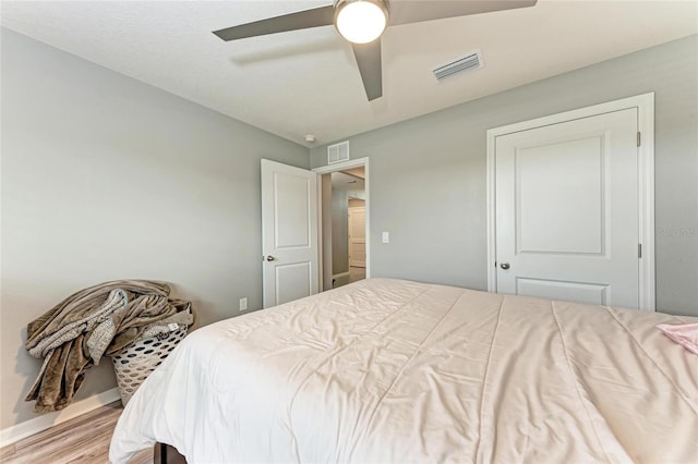 bedroom with light wood-type flooring, baseboards, visible vents, and a ceiling fan