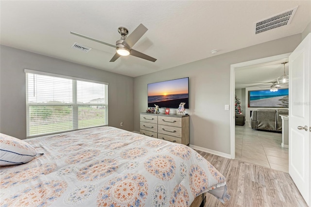 bedroom with visible vents, ceiling fan, light wood-style flooring, and baseboards