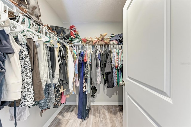 walk in closet with wood finished floors