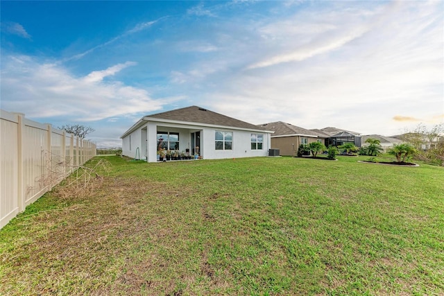 back of house with a yard, central AC unit, fence, and stucco siding