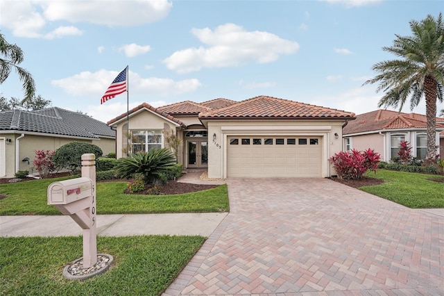 mediterranean / spanish home featuring decorative driveway, a tile roof, french doors, stucco siding, and a garage