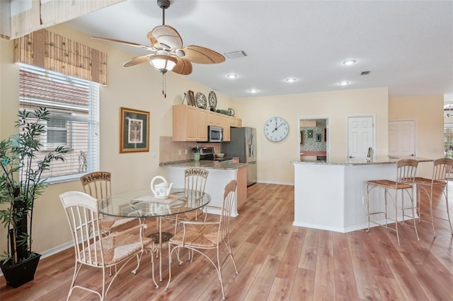 kitchen with stainless steel appliances, light wood-type flooring, visible vents, and backsplash