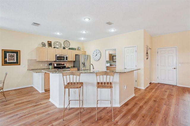 kitchen featuring appliances with stainless steel finishes, visible vents, a kitchen island, and light stone countertops