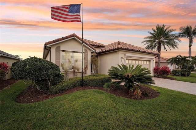 mediterranean / spanish-style home featuring a tile roof, stucco siding, an attached garage, a front yard, and driveway