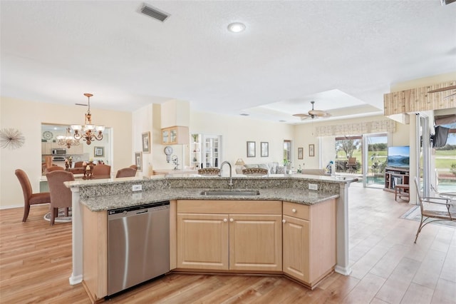 kitchen featuring visible vents, open floor plan, stainless steel dishwasher, pendant lighting, and a sink