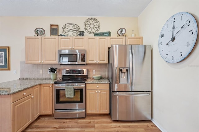 kitchen featuring decorative backsplash, light stone counters, stainless steel appliances, light brown cabinetry, and light wood-style floors