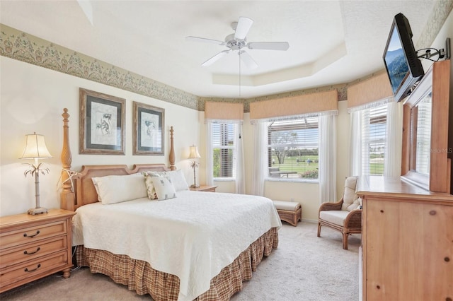 bedroom featuring light carpet, ceiling fan, and a raised ceiling