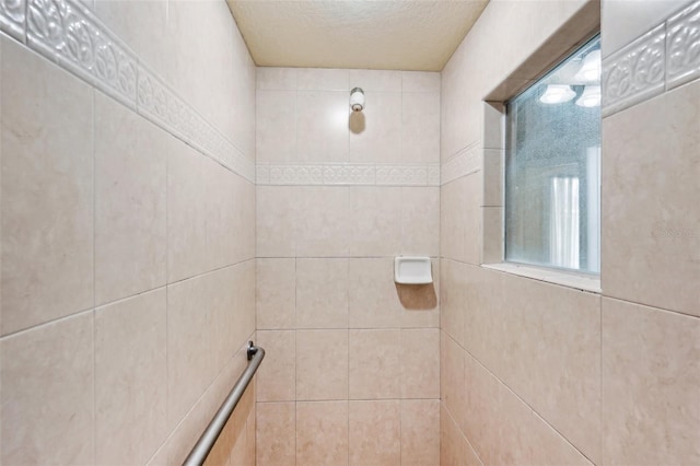 full bathroom featuring a textured ceiling and tiled shower