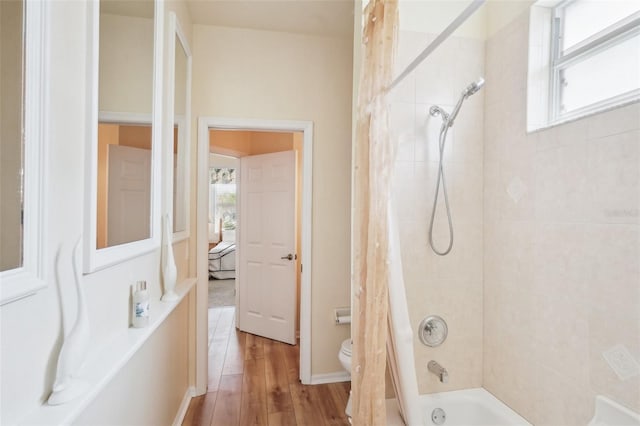 bathroom with toilet, plenty of natural light, shower / tub combo with curtain, and wood finished floors