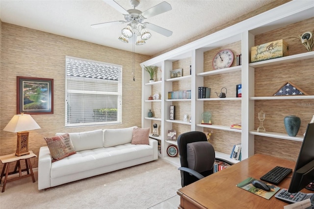 carpeted office with a textured ceiling and a ceiling fan