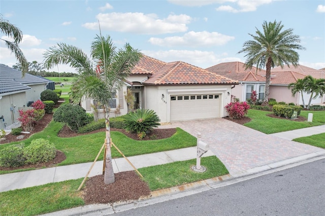 view of front of house with a garage, a tiled roof, decorative driveway, a front lawn, and stucco siding