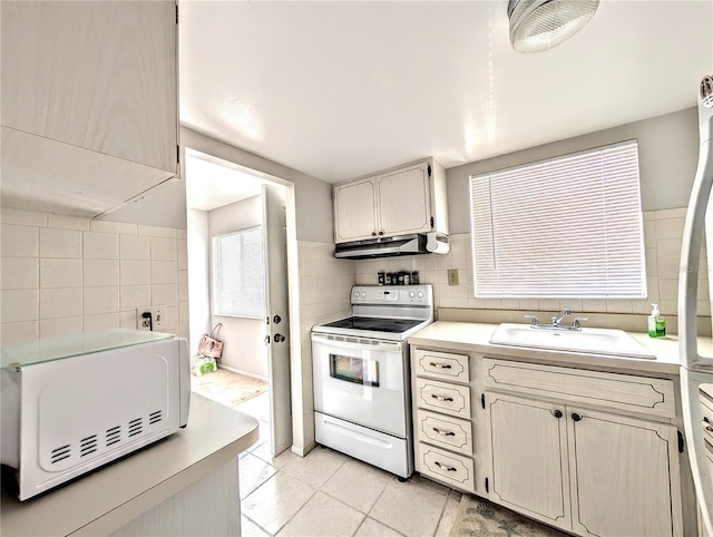 5904 Palm Ln Unit C23, Bradenton, FL 34207 - kitchen featuring white electric range oven, under cabinet range hood, light countertops, light tile patterned flooring, and tile walls