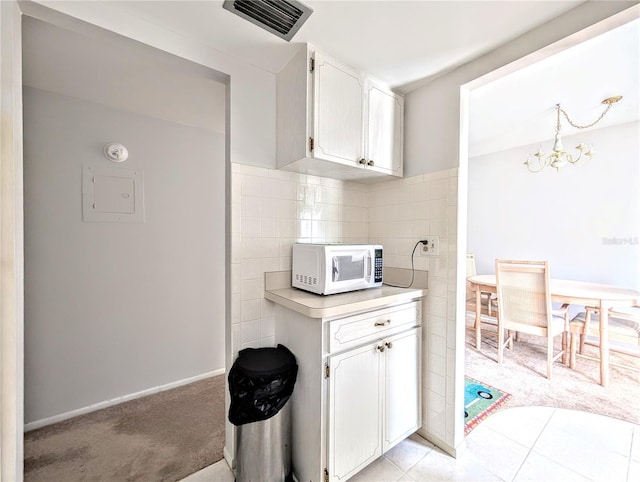 5904 Palm Ln Unit C23, Bradenton, FL 34207 - kitchen with white microwave, light countertops, a chandelier, white cabinetry, and light carpet