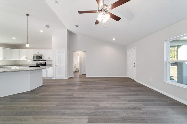 kitchen featuring light stone counters, pendant lighting, stainless steel appliances, open floor plan, and white cabinetry