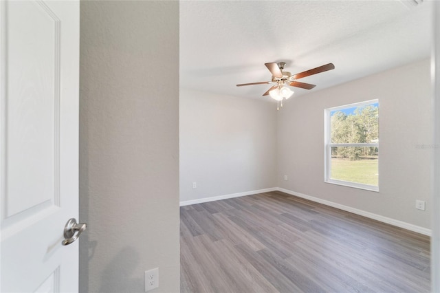 unfurnished room featuring a ceiling fan, light wood-style flooring, and baseboards