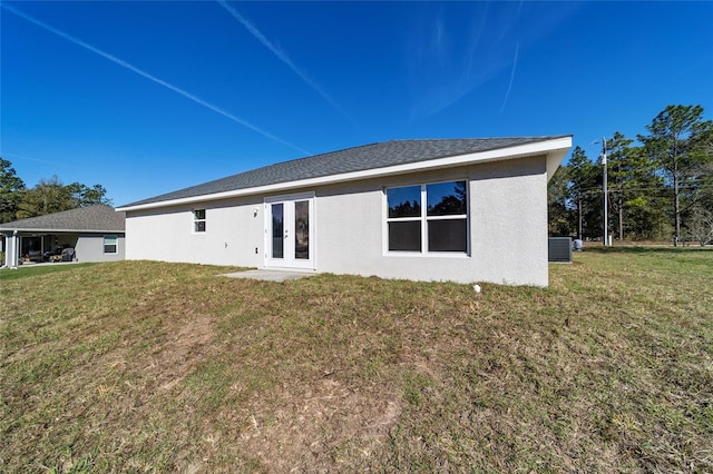 back of property with french doors, a lawn, and stucco siding