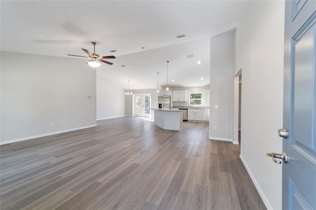 unfurnished living room featuring visible vents, dark wood-type flooring, a textured ceiling, baseboards, and ceiling fan with notable chandelier