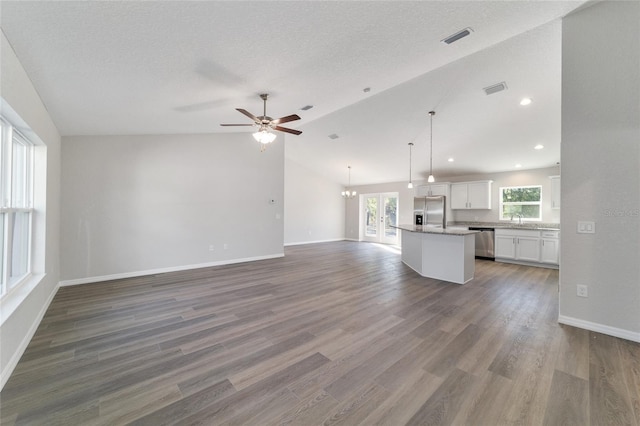 unfurnished living room with visible vents, vaulted ceiling, a sink, and wood finished floors