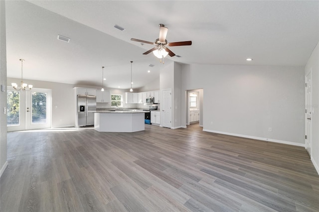 unfurnished living room featuring visible vents, light wood-style flooring, high vaulted ceiling, baseboards, and ceiling fan with notable chandelier