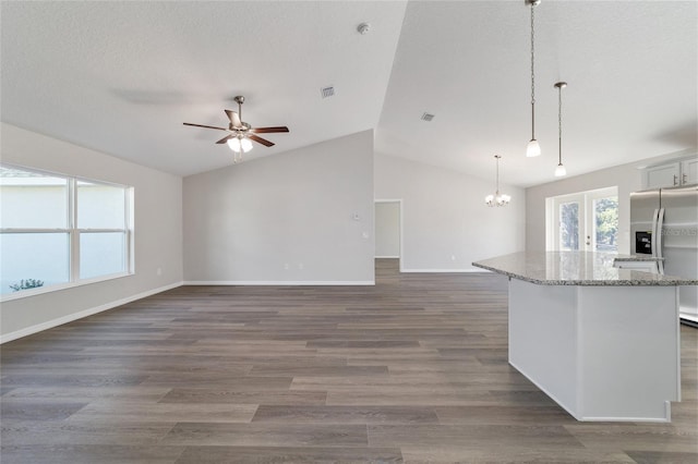 kitchen featuring light stone countertops, white cabinetry, pendant lighting, and open floor plan