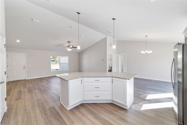 kitchen with open floor plan, a center island, freestanding refrigerator, and white cabinets