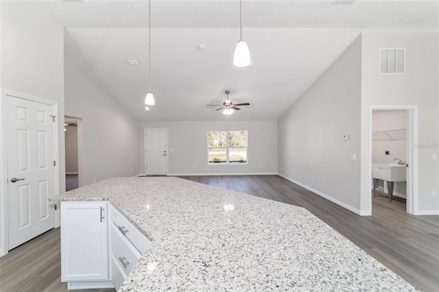 kitchen featuring visible vents, white cabinets, hanging light fixtures, light stone countertops, and vaulted ceiling